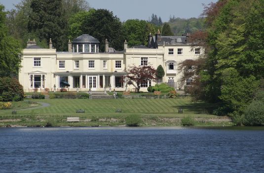 large cream coloured house amongst the trees with a large landscape garden