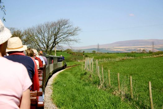 narrow gauge passenger train filled with tourists travelling through the countryside