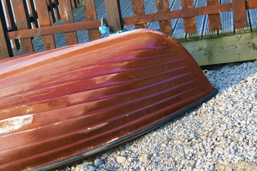 painted upturned boat on lakeside pebbles