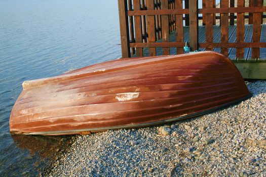 painted upturned boat on lakeside pebbles