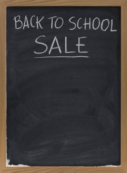 back to schook sale advertisement handwritten with white chalk on a blackboard with eraser smudges, copy space below