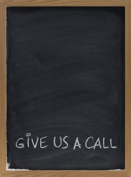 give us a call advertisement hadwritten with white chalk on blackboard, copy space above