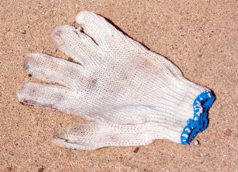 Dirty worker mitten with blue braid rests upon song