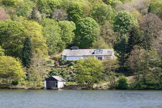 large cream coloured house amongst the trees with a large landscape garden