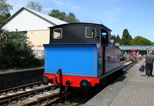 blue steam locomotive coming into the station