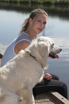 Pretty woman by the waterside with her dog