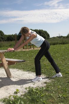 Pretty blond woman doing stretching exercises after her run outdoors