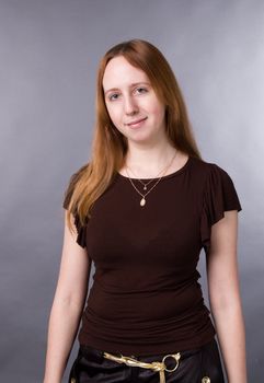 The young girl in brown shirt-blouse on a grey background