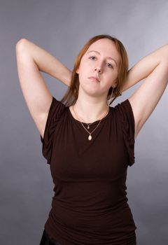 The young girl in brown shirt-blouse on a grey background