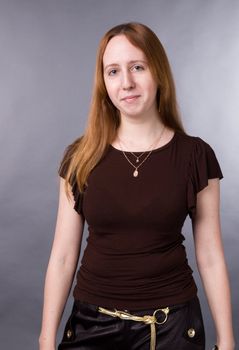 The young girl in brown shirt-blouse on a grey background