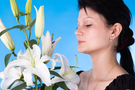 The attractive woman with a bouquet of lilies isolated on a dark blue background.