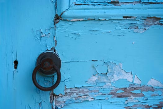 Paint peeling from an old door. Turquoise colour.