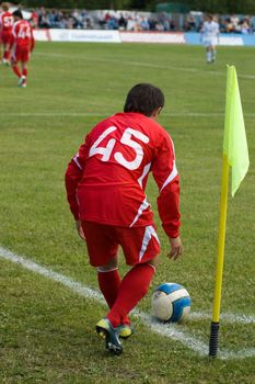 The football player in the red form carries out corner kick