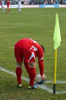 The football player in the red form carries out corner kick
