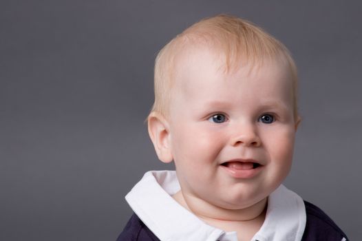 The small smiling child in studio, on a grey background
