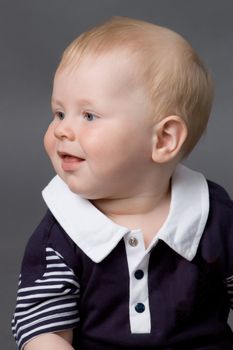 The small smiling child in studio, on a grey background