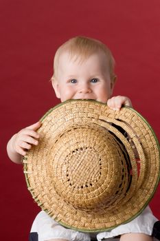 The small smiling child in studio, on a red background