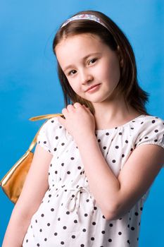 The girl of ten years poses with a gold handbag in a hand