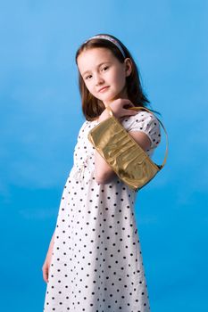 The girl of ten years poses with a gold handbag in a hand