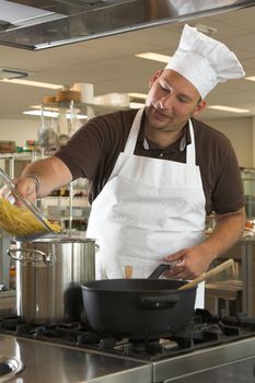 Italian chef adding the pasta to the boiling water