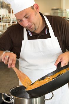 Italian chef moving pasta into another pan