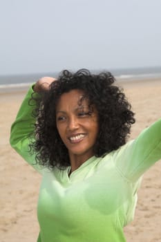 Beautiful black woman stretching herself at the beach