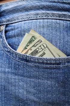 Twenty dollar bills tucked into a woman's jeans hip pocket. Shallow dof with selective focus on cash.
