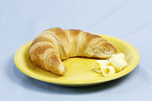 Croissant with butter over light blue background
