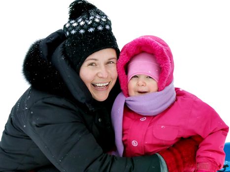 Real mother and daughter all smiles, enjoying winter fun; looking at camera, isolated by the snow.