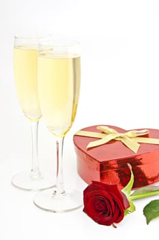 On white champagne glasses, gift box heart in the form of a red rose.
