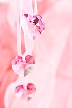Three crystal hearts on a pink background.
