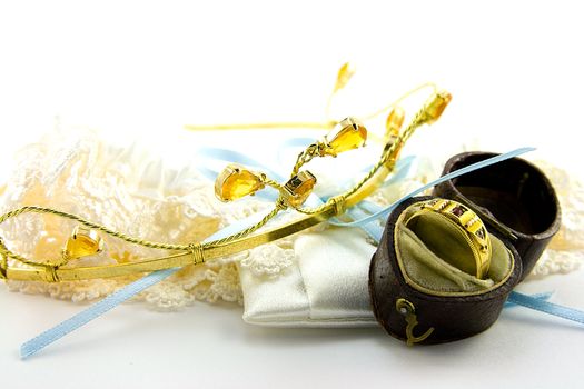 Tiara with lace garter and gold ring in a box on a white background