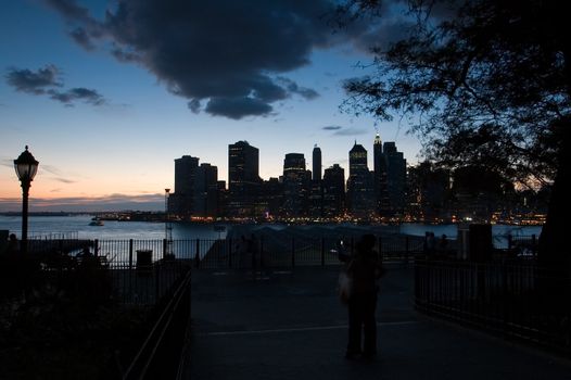 lower manhattan at night, photo taken from brooklyn, figure silhouette in foreground