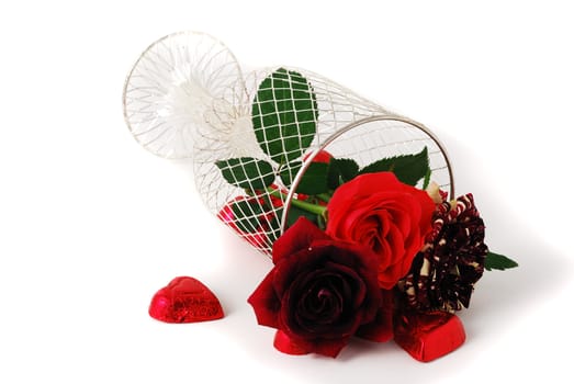 Three different red tint roses in mesh vase and chocolate candies isolated on white background