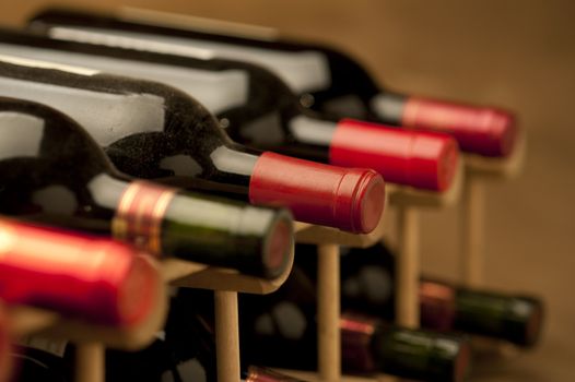 Red wine bottles stacked in rack on warm background