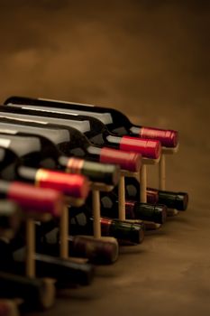 Red wine bottles stacked in rack on warm background