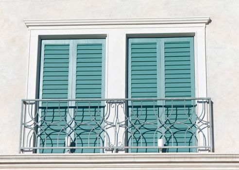 two windows with closed green shutters