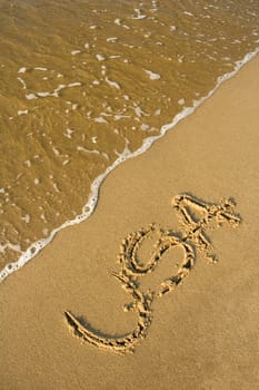 USA written in sand on a beach, calm water 