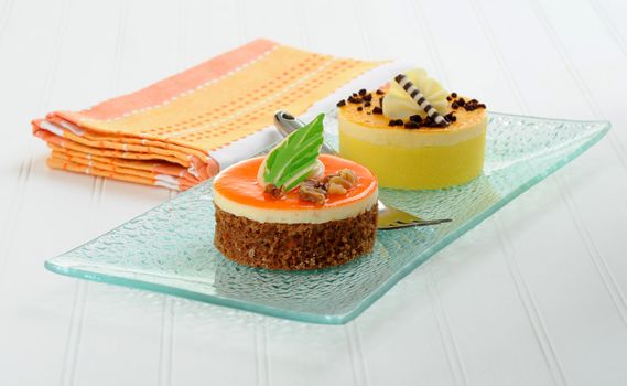 Colorful individual cakes on a glass dish.