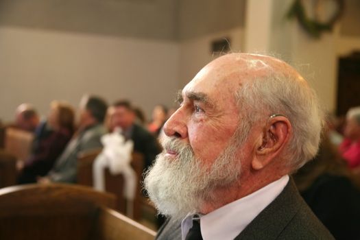 Grandfather sitting in church watching a wedding