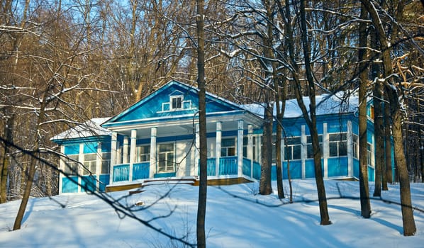 Wooden house with a pitched roof in the winter forest.