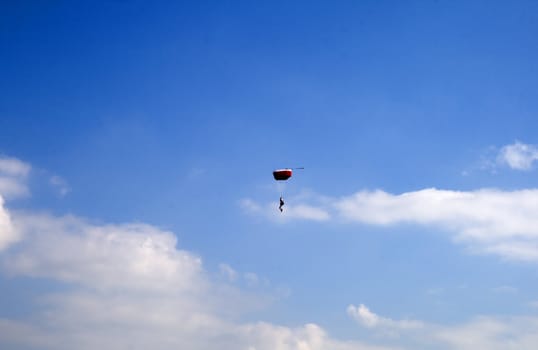 Parachutist flying in blue and cloudy sky