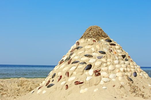 Pyramid of sand and shells on the sea beach