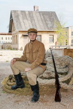 Soldier with a gun in uniform of World War I, sit down on the rope. Costume accord the times of World War I. Photo made at cinema city Cinevilla in Latvia.