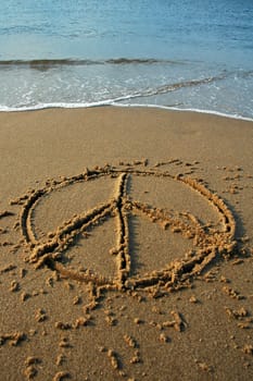 peace sign written in sand on a beach, cyan water in background