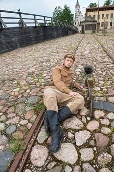 Soldier with gun and boiler in uniform of World War I, resting on the pavement. Costume accord the times of World War I. Photo made at cinema city Cinevilla in Latvia. 
