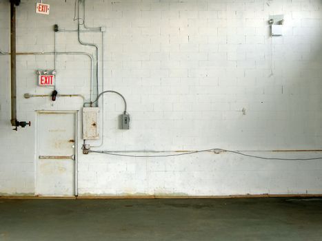 white warehouse wall with exit signs and a door