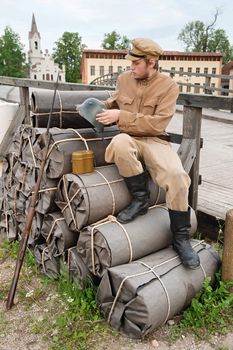 Soldier with helmet and gun sitting on the bundles. Costume accord the times of World War I. Photo made at cinema city Cinevilla in Latvia.