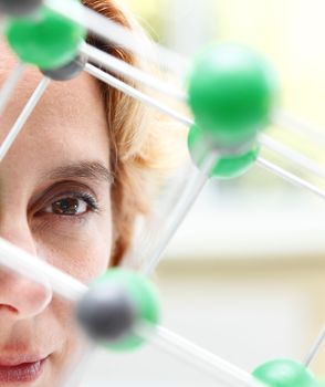 Image of a female researcher eye through a molecular model structure.Selctive focus on the eye.