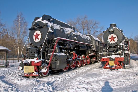 Steam locomotive beside a railway station platform. Winter. Retro train.